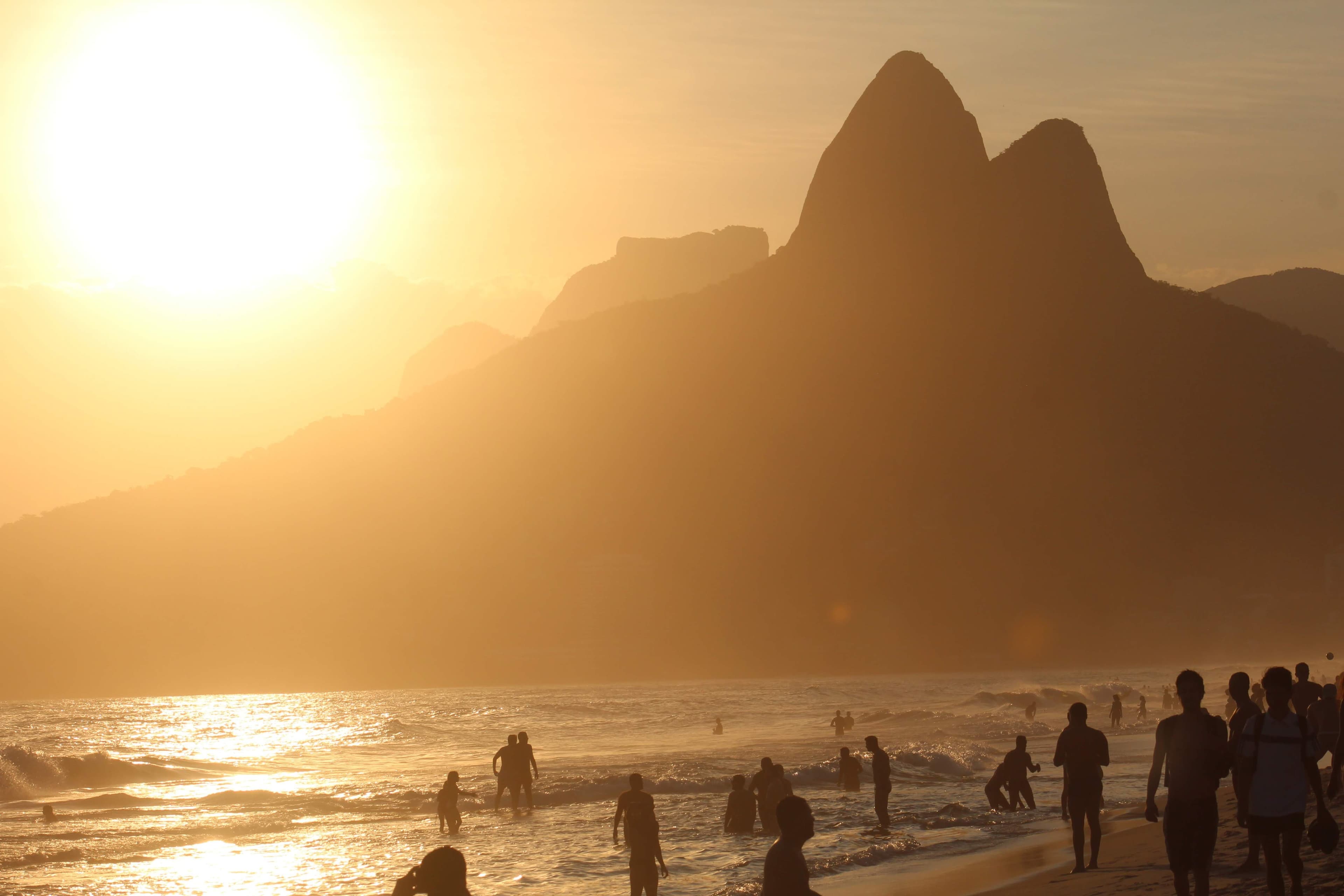 Ipanema beach in Rio de Janeiro at sunset, with the Dois Irmãos peaks in silhouette